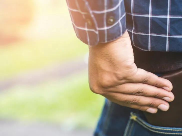 Close-up of a man in casual attire sliding a minimalist wallet into his back pocket. The sleek design of the wallet highlights its compact functionality, perfect for men seeking a blend of style and practicality.