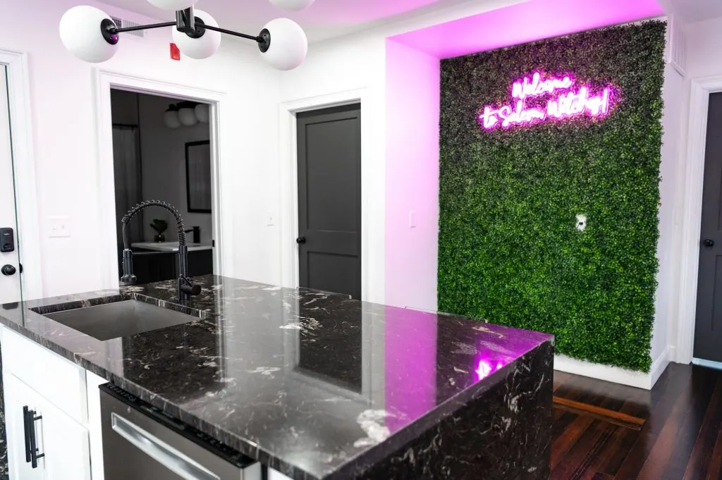 Airbnb Plus modern kitchen with plant wall and neon sign