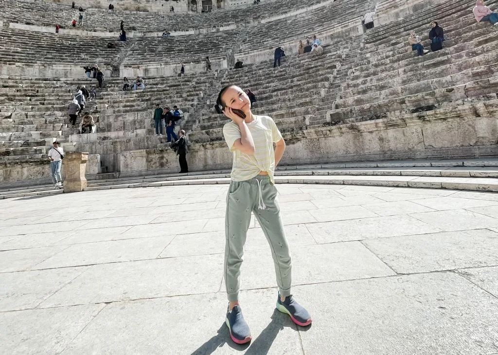 child talking on a cell phone in an ancient stadium