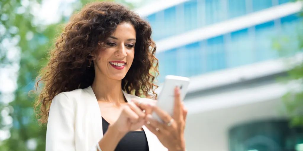 woman tapping on her phone with a smile on her face and not enjoying the nice day