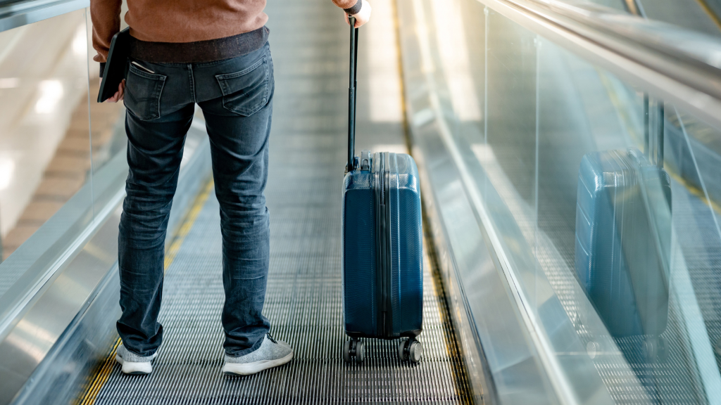 A traveler going to a terminal while carrying his luggage.  