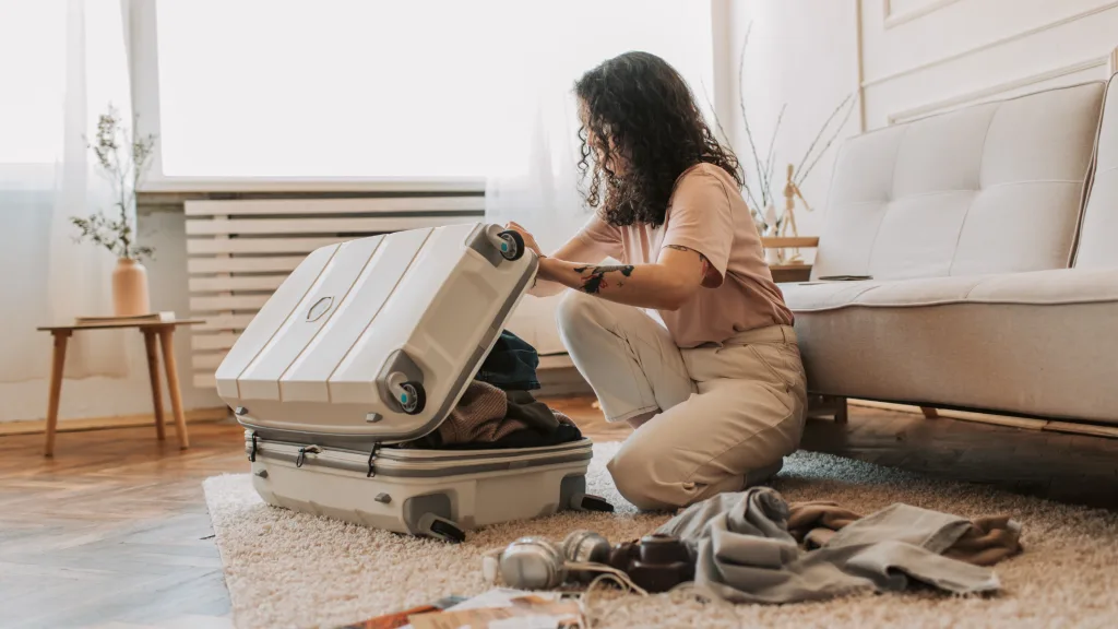 A picture of a woman putting his belongings into a luggage.