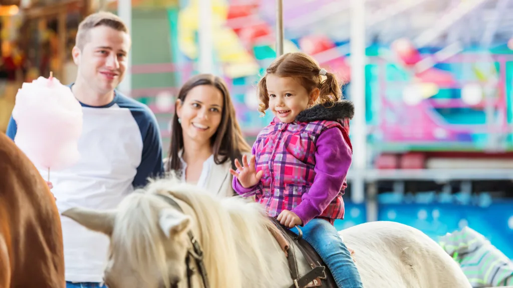 A family visiting an adventure park's horse ride attraction.