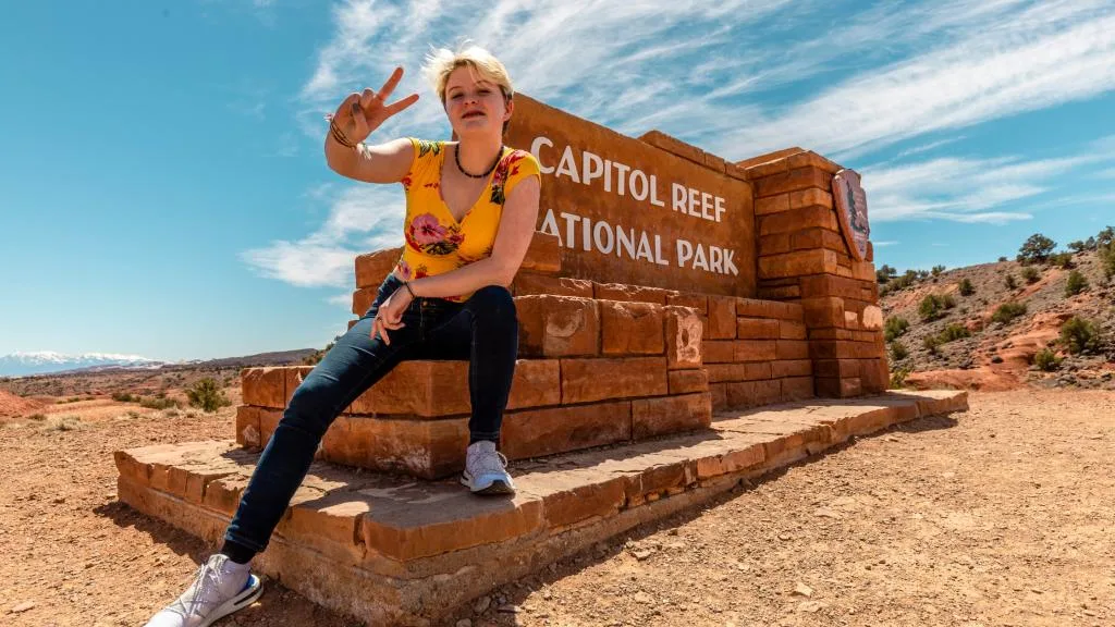 A female teenager posing in front of the Capitol Reef National Park sign. 