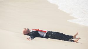 An image of a man in a business suit resting on a beach for an article about "work life balance."