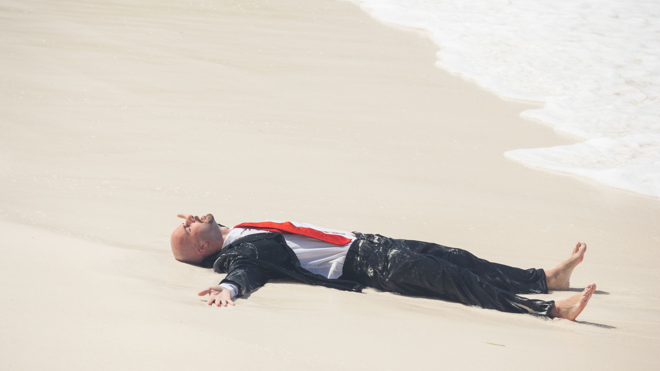 An image of a man in a business suit resting on a beach for an article about "work life balance."