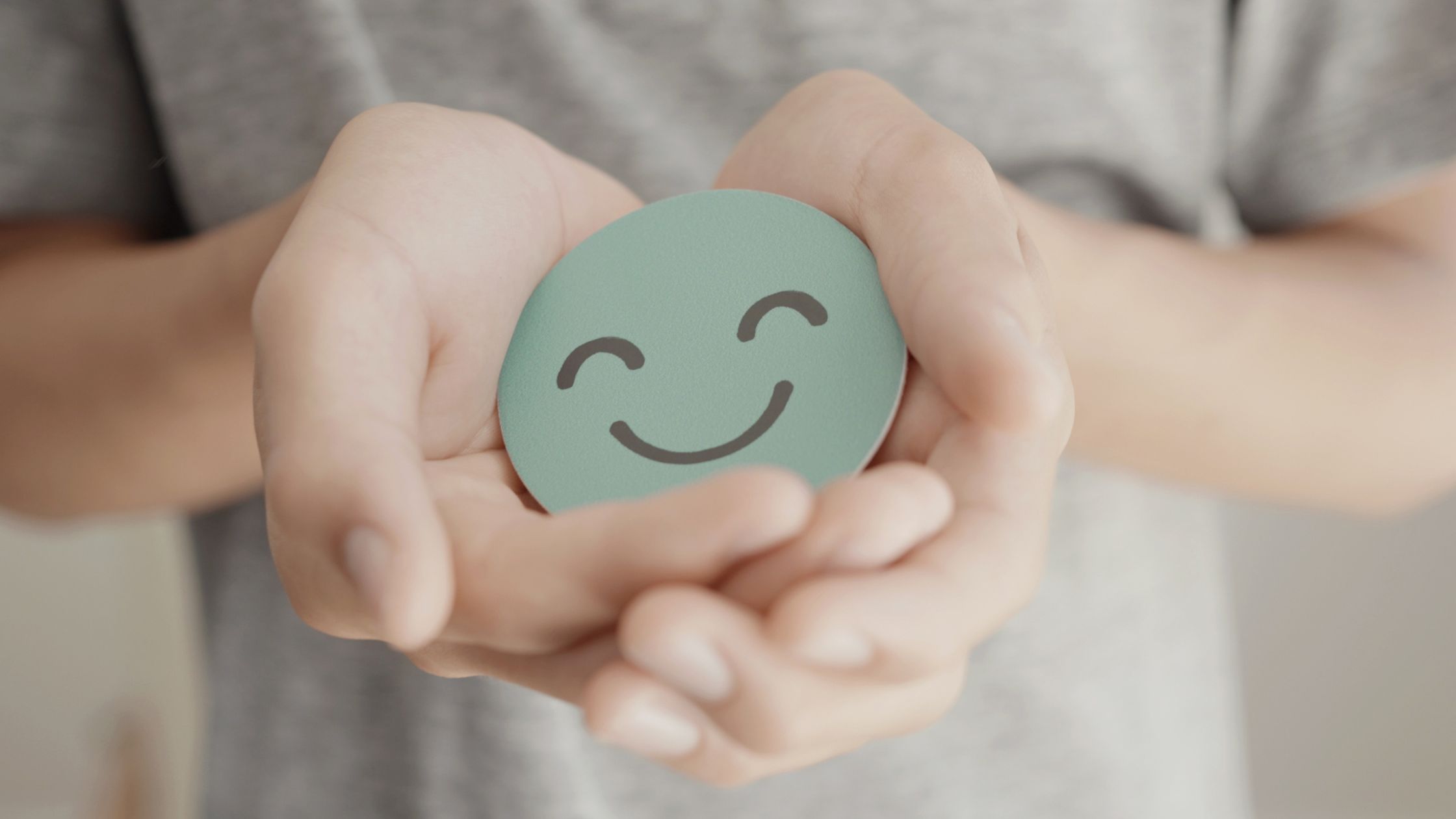 An image of a smiling emoji being held by a person for an article about "mental health for nomads."