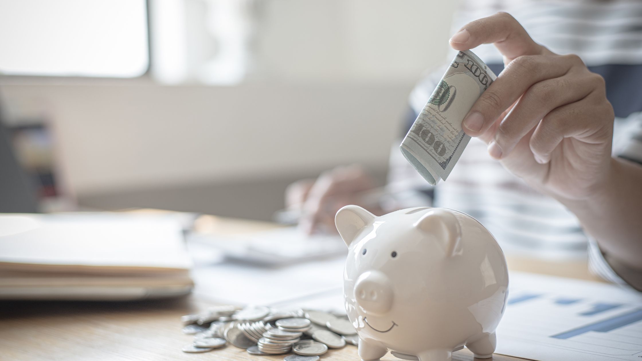 An image of a nomad putting aside money in a piggy bank for an article about "save money as a nomad."