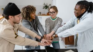 An image of employees and manager joining hands for the article about types of motivation in the workplace.