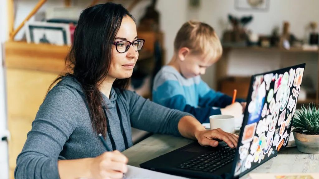 An image of a mom working from home while minding her kid. 