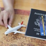 An image of a person holding a toy plane, passport, and a credit card for an article about "how long does it take to improve credit score."