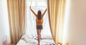 An image of a legally aged traveler opening a window for an article about how old to rent Airbnb.