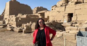 A woman stands confidently in front of ancient ruins, symbolizing reflection and resilience. This image illustrates the importance of grounding yourself in history and action when grappling with an existential crisis. #HowToOvercomeExistentialCrisis
