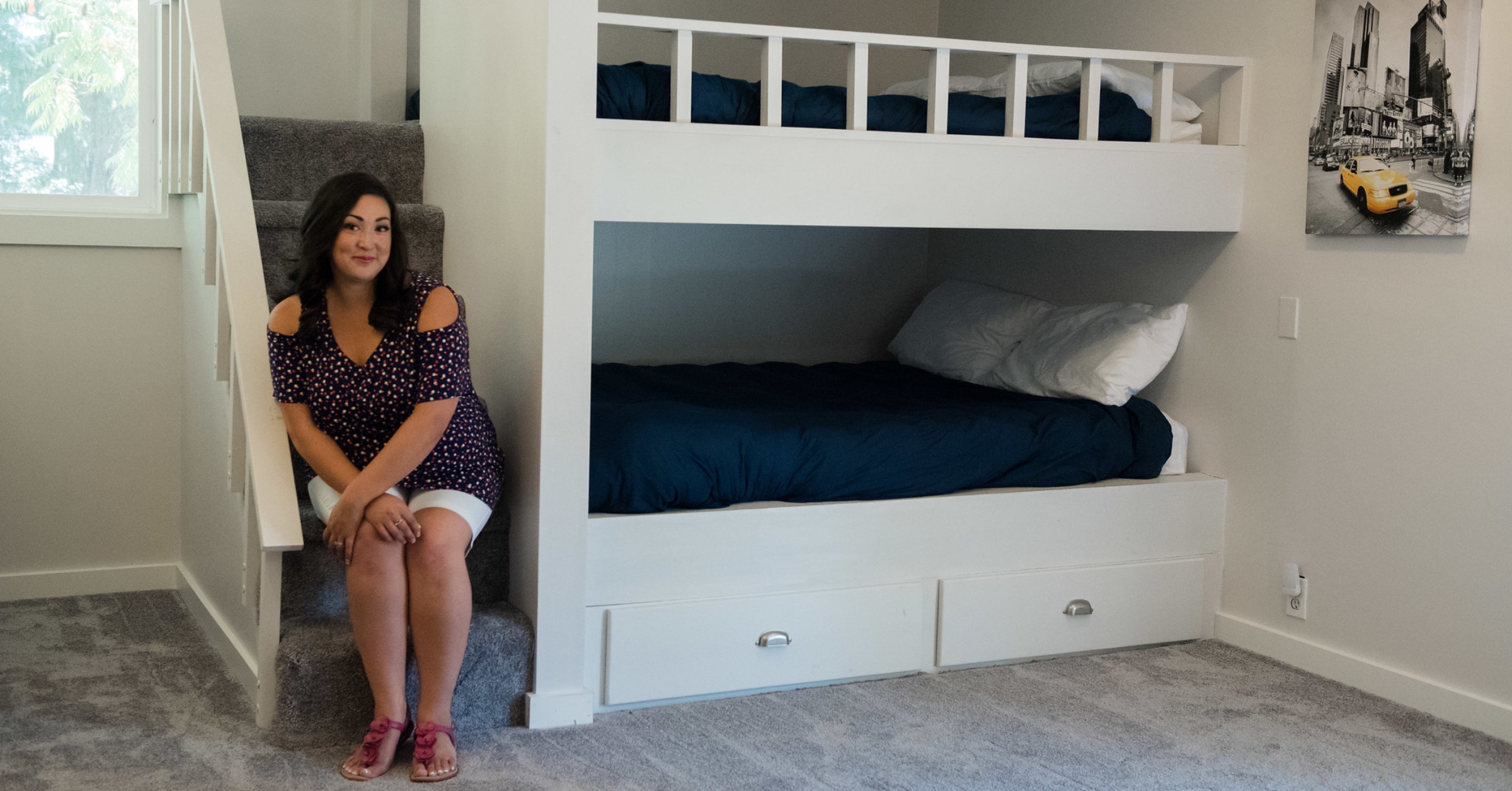 A woman sits by a built-in bunk bed in a neatly arranged, minimalist room, highlighting a cozy and inviting Airbnb setup. This image conveys the appeal of thoughtfully designed spaces in short-term rentals, addressing the question of whether the Airbnb dream is still achievable amidst changing industry trends in 2025.