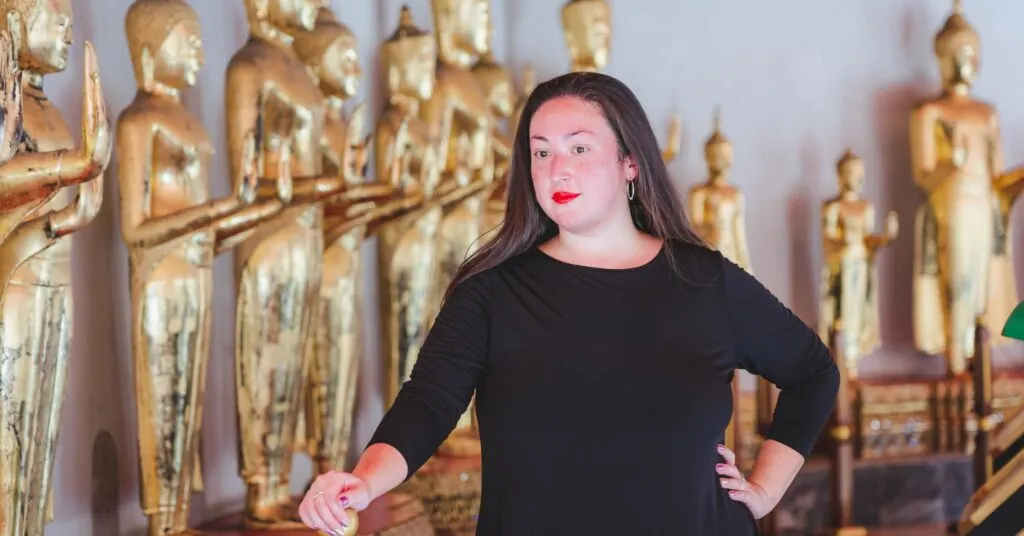 A woman stands confidently in front of a row of golden statues, symbolizing self-discovery and personal empowerment. This image aligns with themes of overcoming existential crises through self-awareness and taking control of one’s path. #HowToOvercomeExistentialCrisis