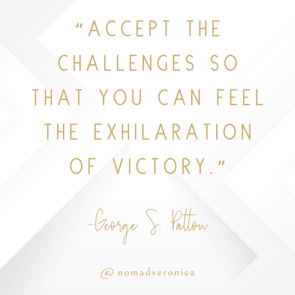 The quote, "Accept the challenges so that you can feel the exhilaration of victory," by George S. Patton, is displayed in sophisticated gold typography on a clean white geometric background. This motivational message underscores the theme of overcoming adversity, fitting seamlessly into the "11 Uplifting Quotes About Overcoming Challenges" section of the blog. The author's name and the handle "@nomadveronica" are prominently featured, maintaining a cohesive and elegant style.