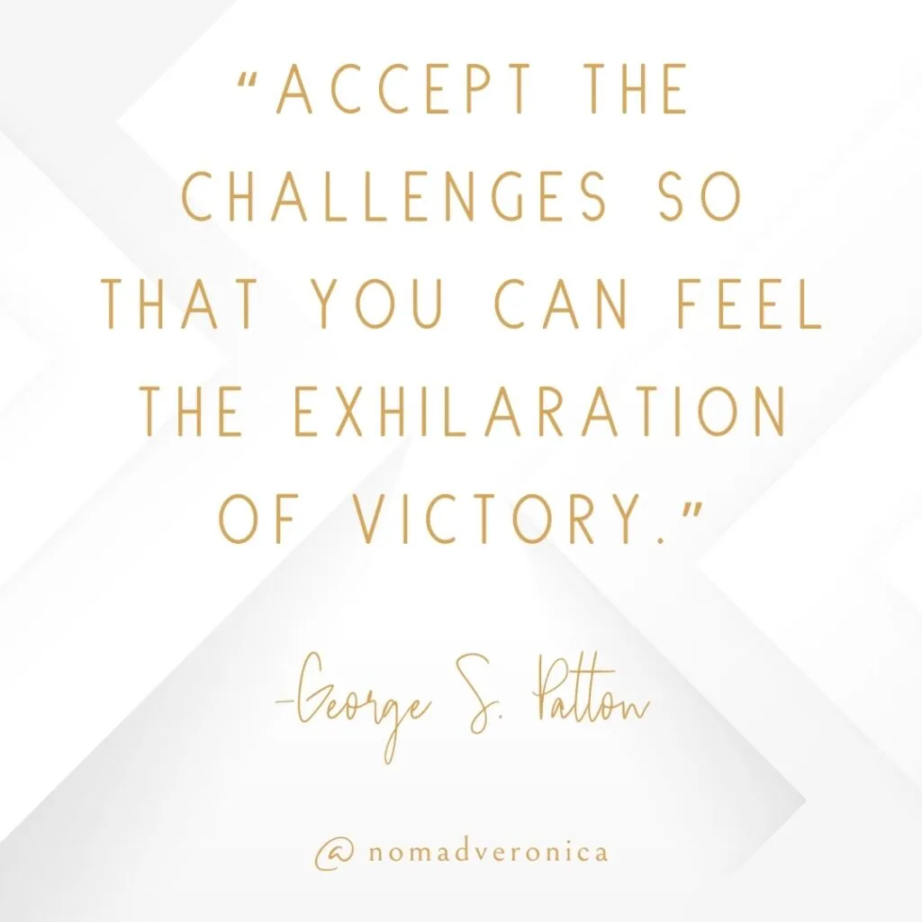 The quote, "Accept the challenges so that you can feel the exhilaration of victory," by George S. Patton, is displayed in sophisticated gold typography on a clean white geometric background. This motivational message underscores the theme of overcoming adversity, fitting seamlessly into the "11 Uplifting Quotes About Overcoming Challenges" section of the blog. The author's name and the handle "@nomadveronica" are prominently featured, maintaining a cohesive and elegant style.