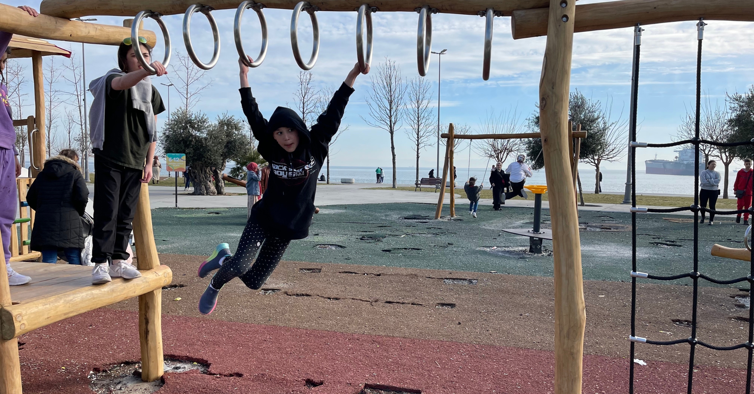 Children playing on a wooden playground near a waterfront in Istanbul, showcasing a family-friendly environment. Perfect for families looking for places to stay in Istanbul with access to outdoor activities and scenic views.