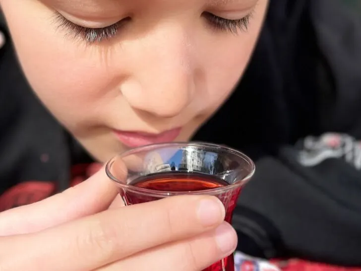 Close-up of a child enjoying traditional Turkish tea in a tulip-shaped glass, reflecting Istanbul's vibrant culture and culinary offerings found at the best restaurants in Istanbul.