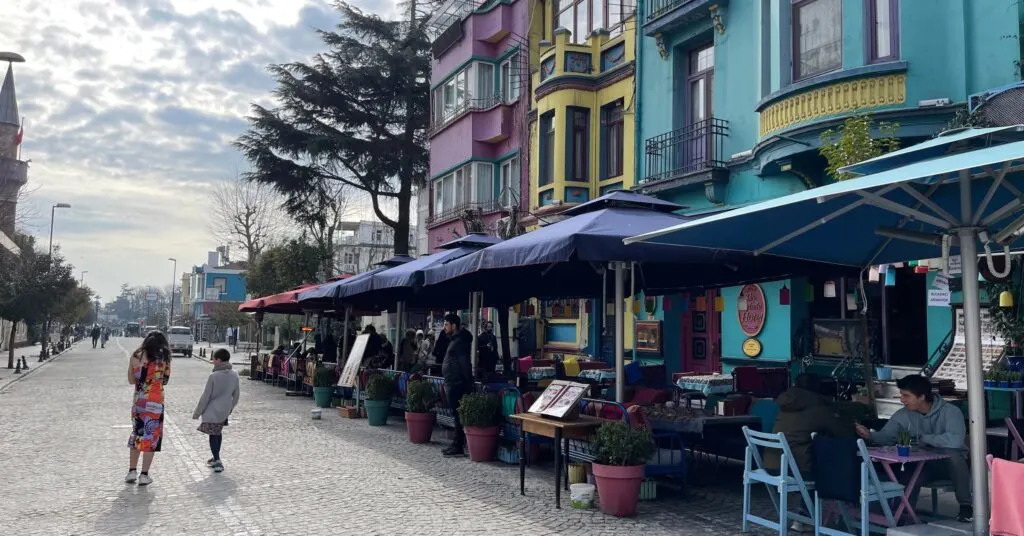 Two children walking down a colorful street in Istanbul, lined with vibrant cafes and historic buildings, perfect for a leisurely day during a 5 days in Istanbul family-friendly itinerary.