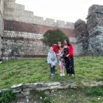 A family standing in front of the historic walls of Istanbul, surrounded by greenery, perfect for a 5 days in Istanbul itinerary that highlights cultural and family-friendly experiences.