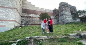 A family standing in front of the historic walls of Istanbul, surrounded by greenery, perfect for a 5 days in Istanbul itinerary that highlights cultural and family-friendly experiences.
