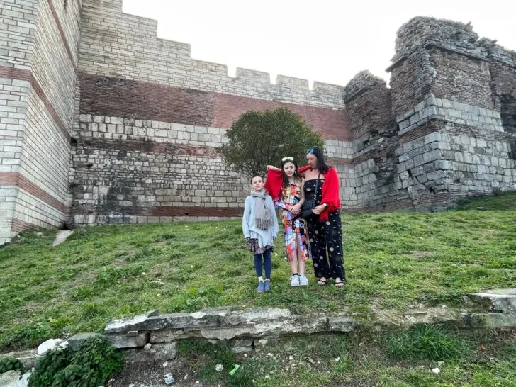 A family standing in front of the historic walls of Istanbul, surrounded by greenery, perfect for a 5 days in Istanbul itinerary that highlights cultural and family-friendly experiences.