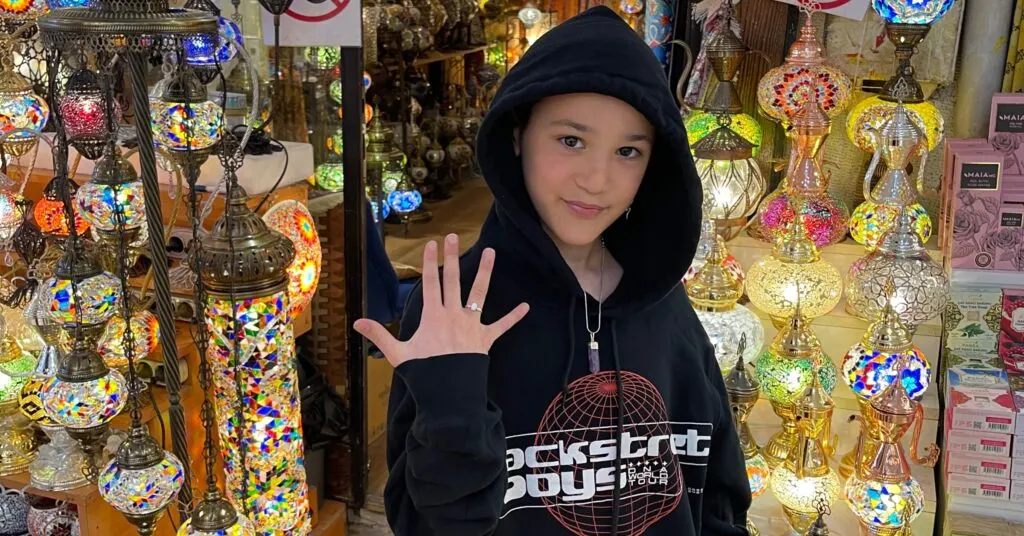 A child posing in front of vibrant mosaic lamps at Istanbul's Grand Bazaar, showcasing one of the must-visit cultural stops during a 5 days in Istanbul family-friendly itinerary.