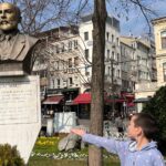 A child pointing at a statue of Mehmet Akif Ersoy in a public square in Istanbul, surrounded by historical buildings and gardens, showcasing educational and cultural things to do in Istanbul, Turkey, with kids.