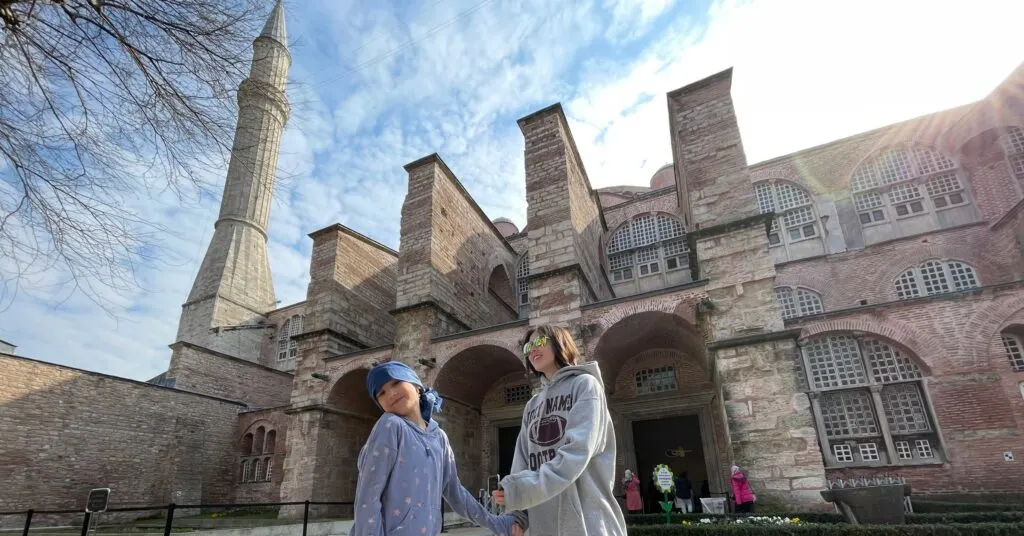 Two children standing in front of the iconic Hagia Sophia in Istanbul, a must-visit landmark included in a 5 days in Istanbul family-friendly itinerary, blending history and cultural exploration.