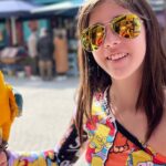 A smiling child holding a vibrant yellow-and-blue parrot at a colorful outdoor market in Istanbul. A unique and interactive experience, perfect for families exploring fun things to do in Istanbul with kids.