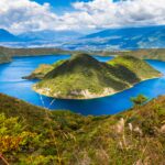 A stunning view of a blue crater lake in Ecuador, surrounded by lush green mountains. A must-visit spot for any Ecuador expat looking for breathtaking natural beauty.