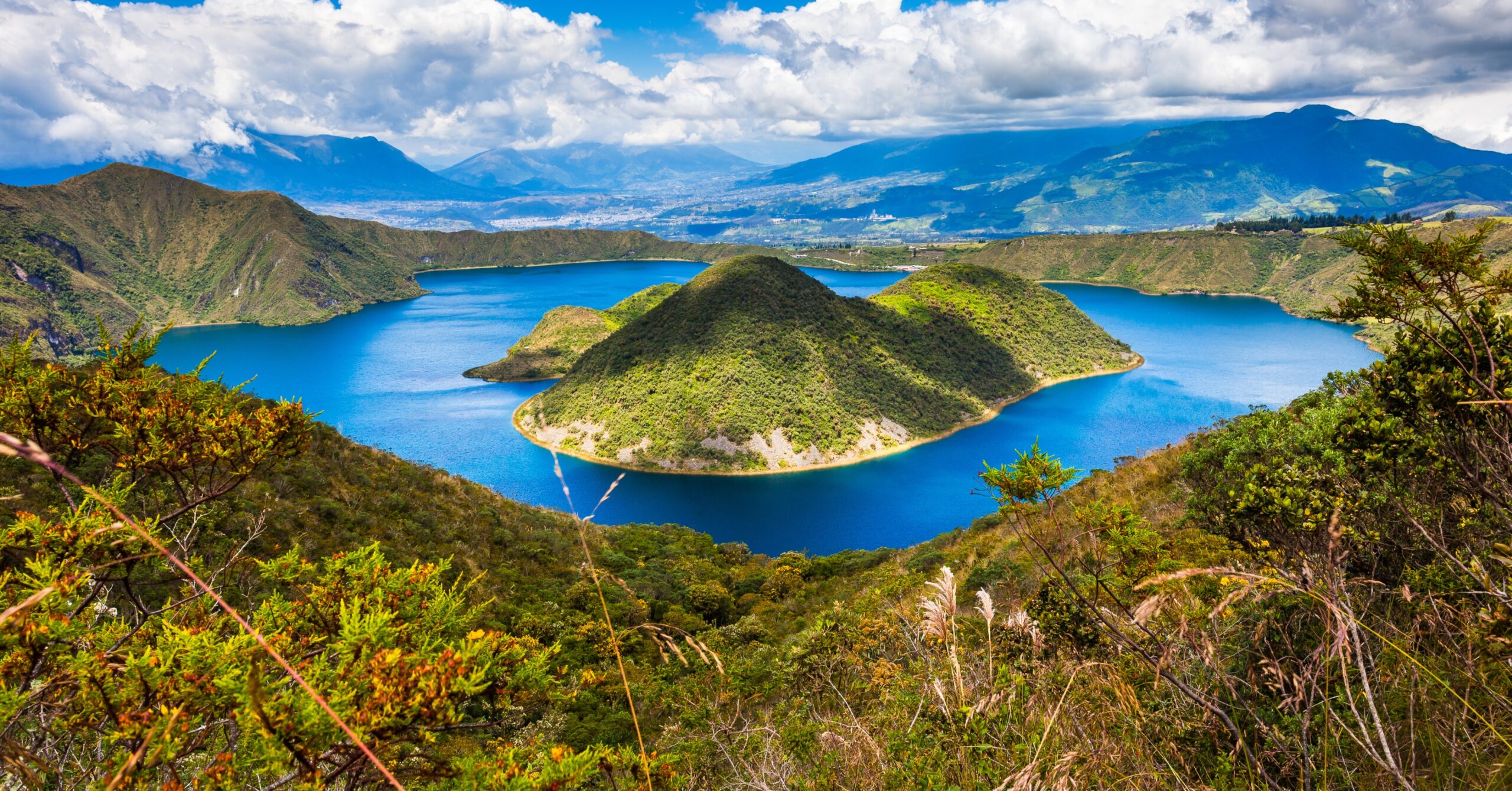 A stunning view of a blue crater lake in Ecuador, surrounded by lush green mountains. A must-visit spot for any Ecuador expat looking for breathtaking natural beauty.