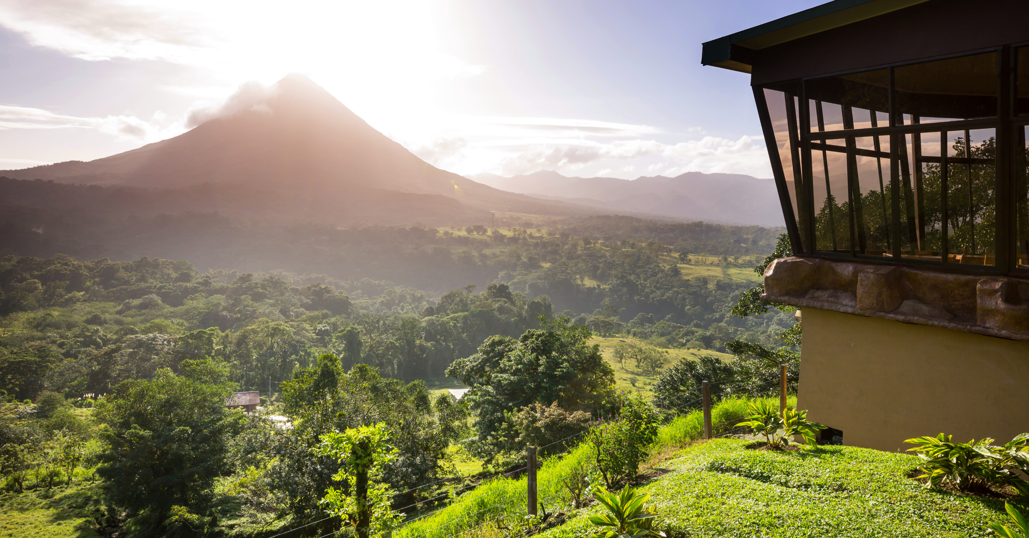 The Arenal Volcano standing majestically at sunrise, surrounded by vibrant green forests. Living near natural wonders like this is a major perk of moving to Costa Rica.