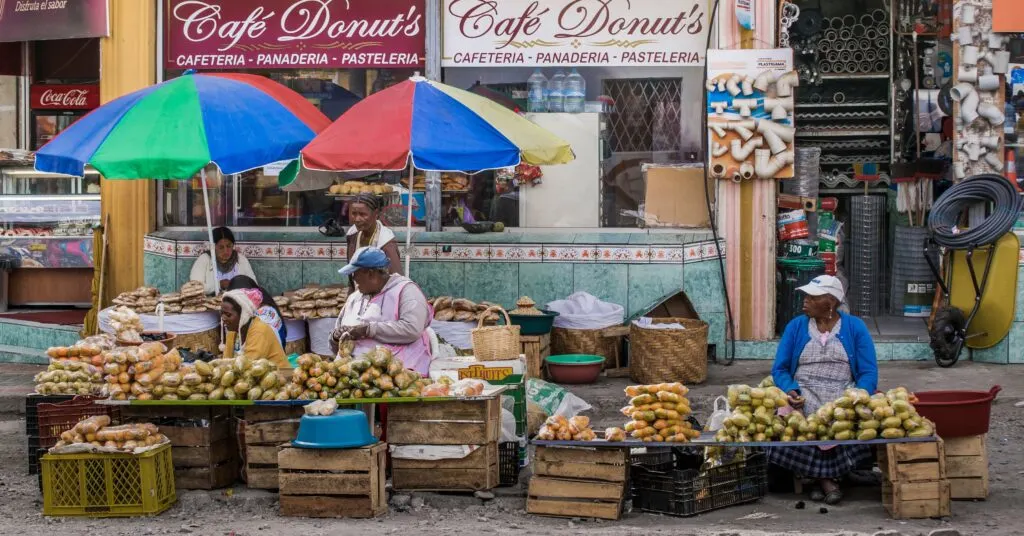 Local vendors at an open-air market in Ecuador selling fresh produce and baked goods. A glimpse into the daily life of an Ecuador expat experiencing authentic local markets.