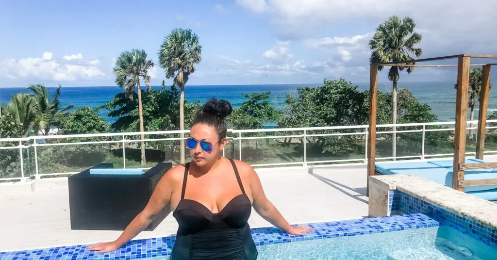 Woman relaxing in a rooftop infinity pool overlooking the ocean, capturing the resort-style lifestyle of living in Dominican Republic.