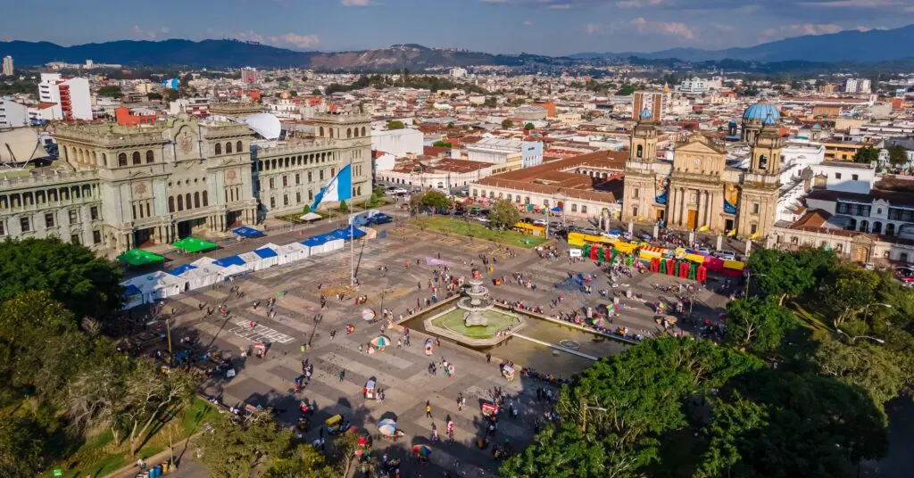 A bustling aerial view of Guatemala City's central square, home to the National Palace and Metropolitan Cathedral. A major hub of history and daily life for expats moving to Guatemala.