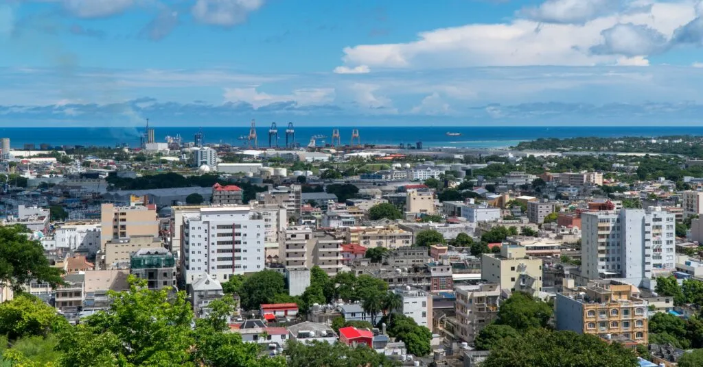 A panoramic view of Port Louis, Mauritius, with its mix of modern high-rises, colonial buildings, and the ocean in the background. The capital city offers expats a balance of work and leisure.