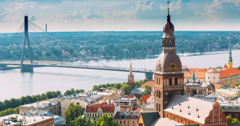 An aerial shot of Riga featuring the Daugava River, the Vanšu Bridge, and the iconic Riga Cathedral clock tower — a perfect snapshot of urban beauty while living in Latvia.