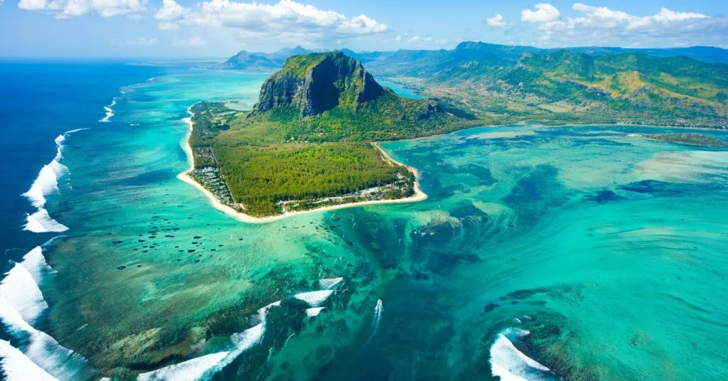 A breathtaking aerial shot of Le Morne Brabant, a UNESCO World Heritage Site in Mauritius, surrounded by turquoise waters and lush greenery. A dream location for expats who love the outdoors.