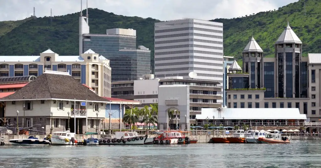 A mix of contemporary buildings, boats, and a colonial-style structure at the waterfront in Mauritius. The island blends history and modernity, making it a top choice for expats.