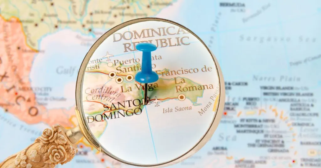 A magnifying glass highlighting the Dominican Republic on a map with a blue pin in Santo Domingo, representing navigation and planning for living in Dominican Republic.