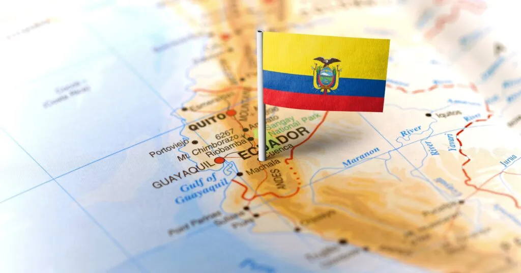 A close-up of a map highlighting Ecuador, with a small Ecuadorian flag pinned near Quito. A useful visual for Ecuador expats planning their move.