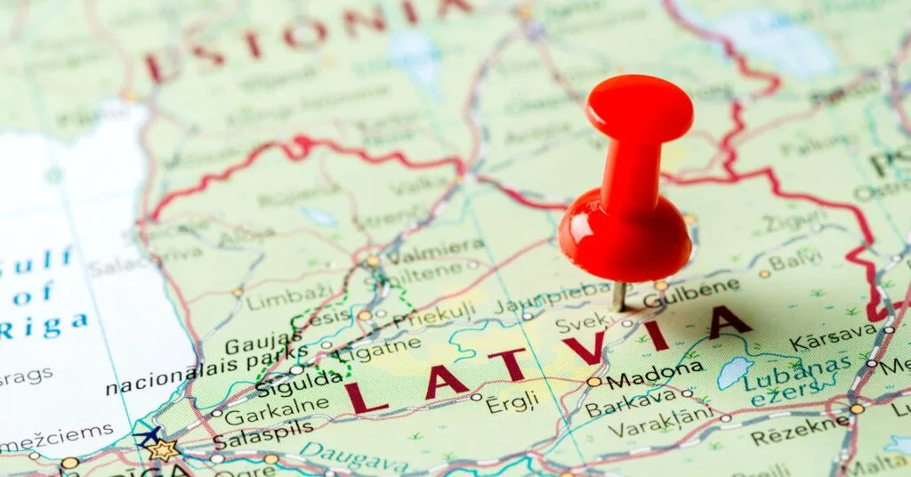 A close-up of a map with a red pushpin marking Latvia, highlighting its geographic location in Northern Europe — a simple visual representing the journey of moving and living in Latvia.