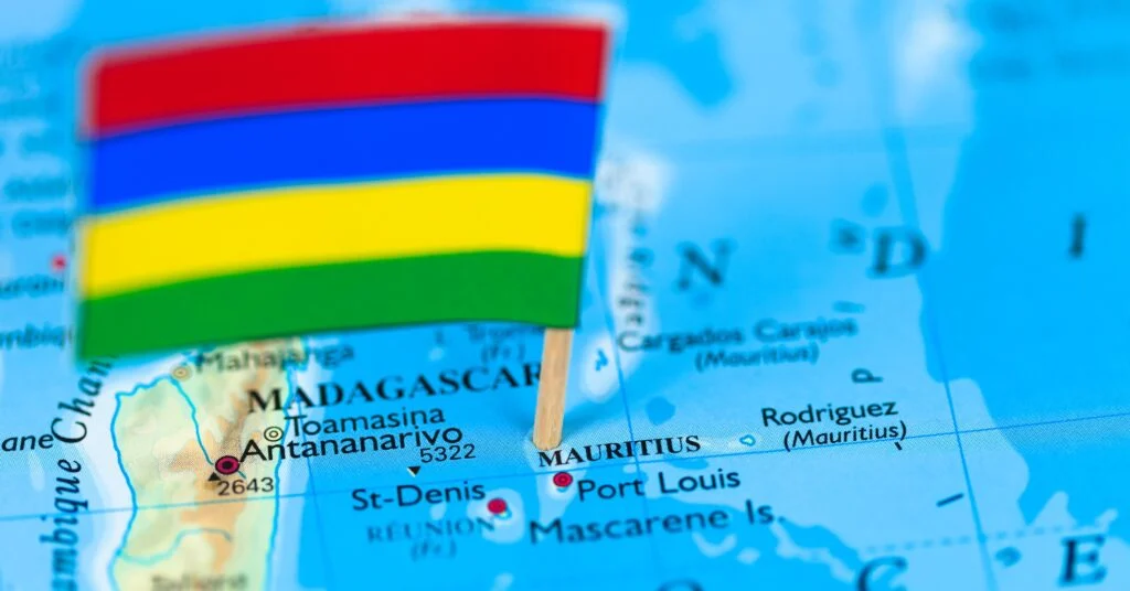 A close-up of a map showing Mauritius, with a miniature national flag pinned to the island. Many expats choose Mauritius for its stunning beaches and business opportunities.