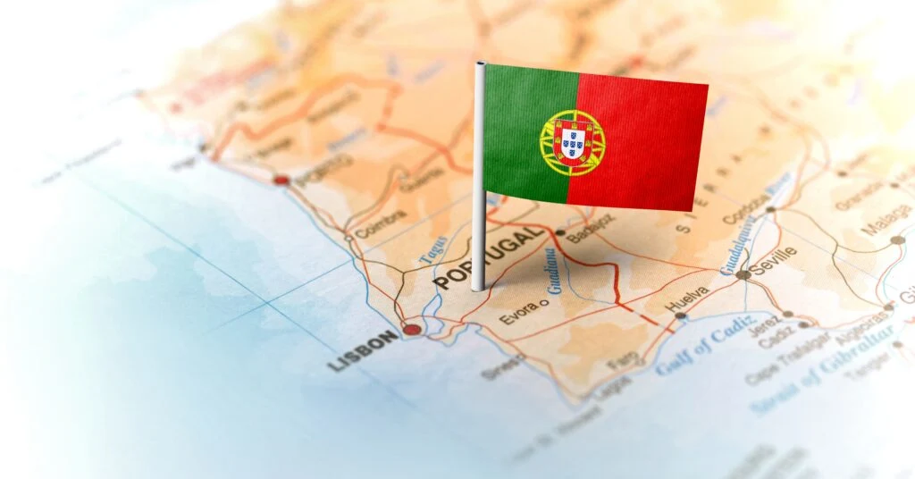 A close-up of a Portugal map with a small flag pinned on the capital, Lisbon. Perfect for anyone thinking of moving to Portugal and planning their next big adventure.