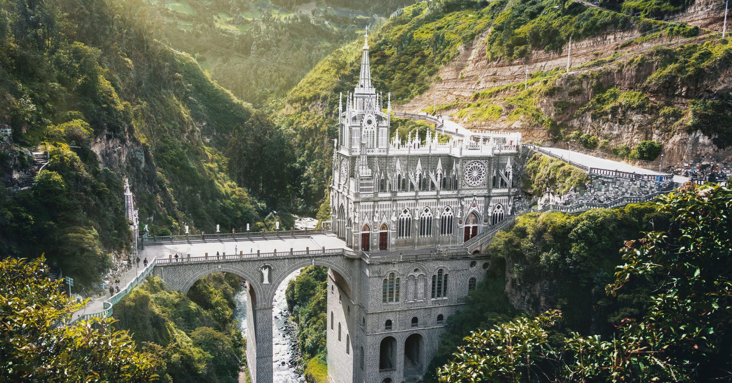 American expats walking across the Las Lajas Sanctuary bridge in southern Colombia surrounded by lush green mountains
