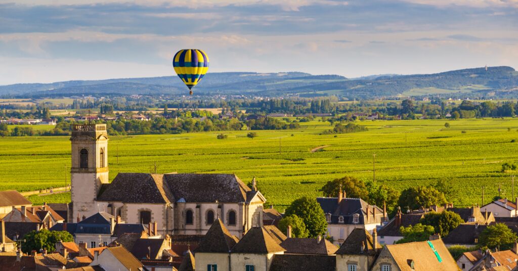 Peaceful hot air balloon floating above the Burgundy countryside, showing why retirees love moving to France for a slower lifestyle