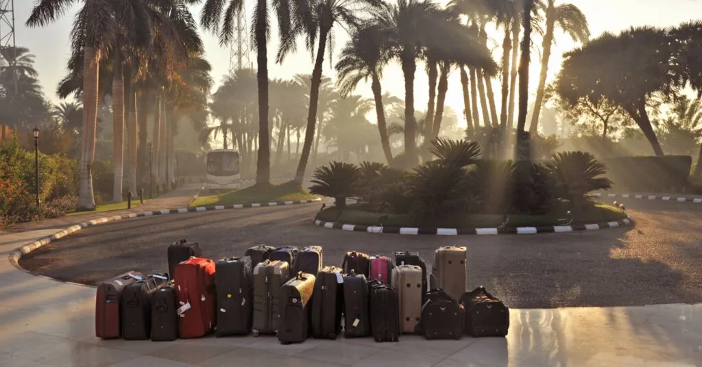 Dozens of suitcases gathered near a palm-lined resort entrance during sunrise, symbolizing the start of relocation to one of the cheapest countries to move for a better lifestyle.