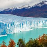 Massive ice wall of the Perito Moreno Glacier meeting turquoise waters, surrounded by fall foliage — a dramatic highlight of southern Argentina for adventurous expats.